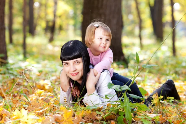 Hermosa joven madre y su hija acostada en el otoño leav —  Fotos de Stock