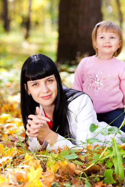 Hermosa joven madre y su hija acostada en el otoño leav — Foto de Stock