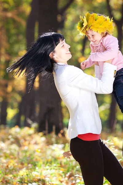 メープルの花輪で彼女の娘を保持している美しい若い母親 — ストック写真