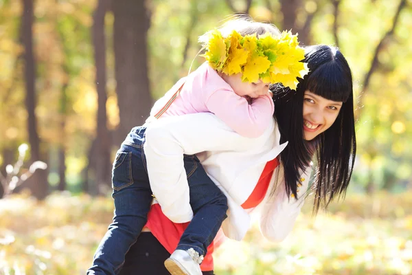 Vacker ung mamma håller sin dotter i en krans av lönn — Stockfoto