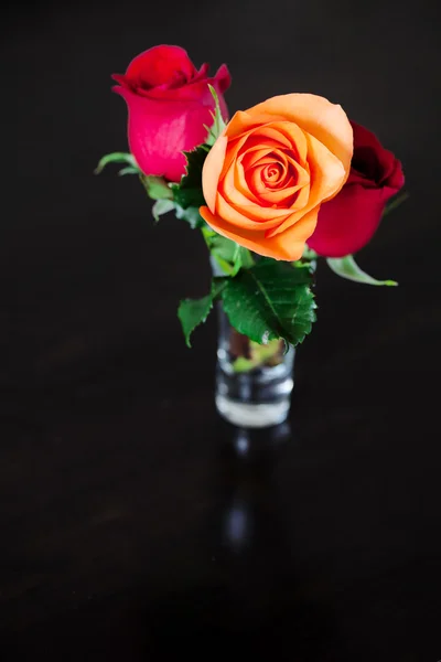 Bukett med fargerike roser i en vase på et trebord – stockfoto