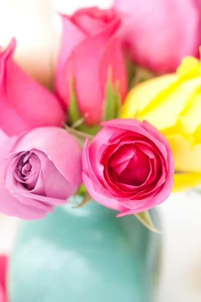 Ramo de rosas de colores en jarrón y pétalos — Foto de Stock