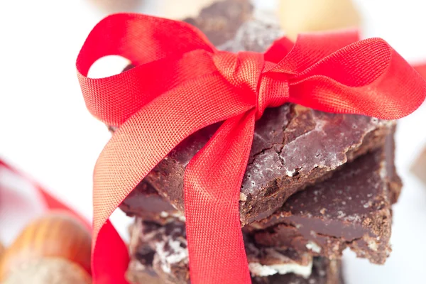 Tło stosu czekolady z czerwoną wstążką i orzechów — Zdjęcie stockowe