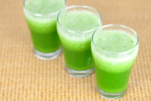 Three glasses with celery juice on wooden mat — Stock Photo, Image