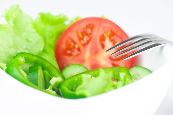 Tenedor, lechuga, tomate, pepino y pimienta en un tazón aislado en — Foto de Stock