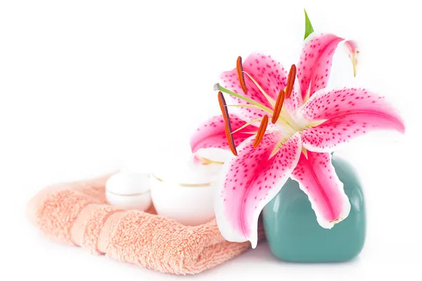 Hermoso lirio en un jarrón, toalla y recipientes cosméticos —  Fotos de Stock
