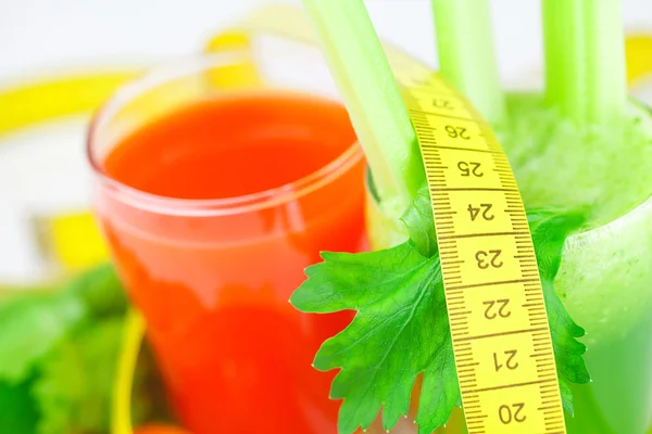 Measuring tape, glass of celery juice and glass of carrot juice — Stock Photo, Image