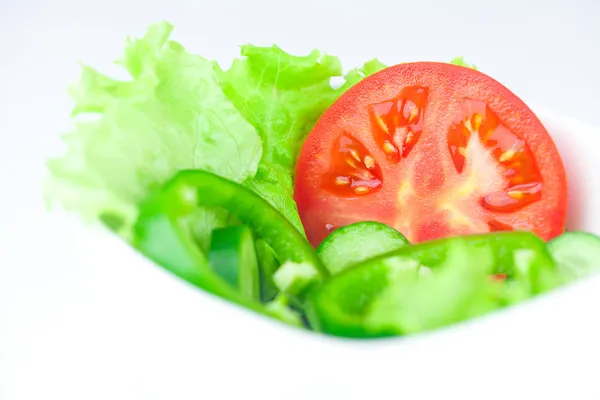 Lechuga, tomate, pepino y pimienta en un tazón aislado sobre blanco — Foto de Stock