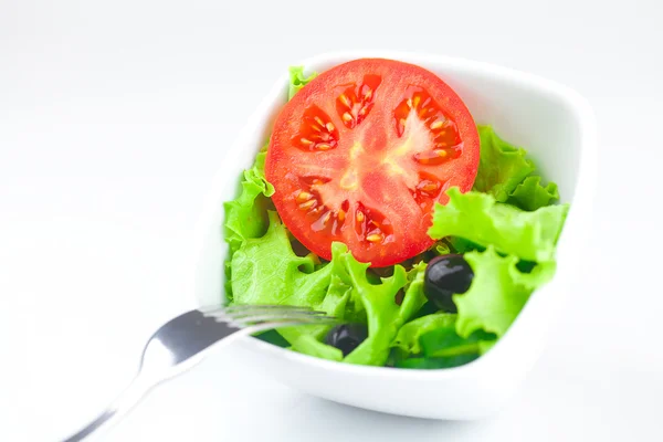 Tenedor, lechuga, tomate, pepino y pimienta en un tazón aislado en — Foto de Stock