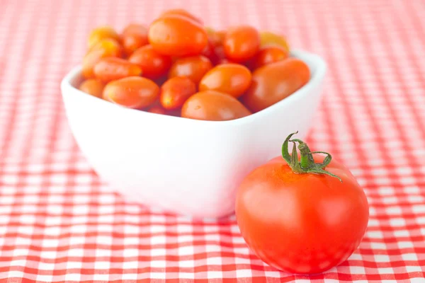Tomates cherry y tomates en tazón sobre tela a cuadros — Foto de Stock