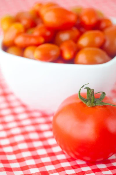 Tomates cherry y tomates en tazón sobre tela a cuadros — Foto de Stock