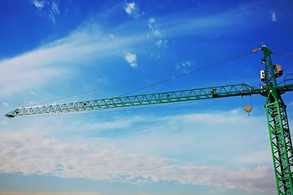 Tower crane above the city on a background of blue sky — Stock Photo, Image