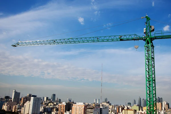 Tower crane above the city on a background of blue sky — Stock Photo, Image