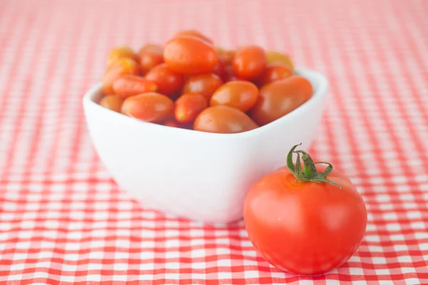 Pomodoro ciliegia e pomodoro in ciotola su tessuto a quadretti — Foto Stock