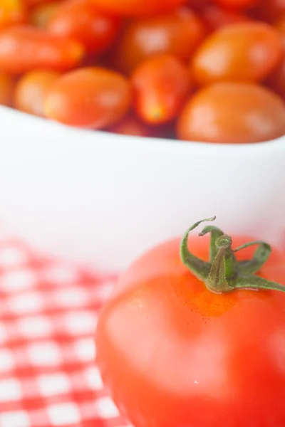 Tomates cherry y tomates en tazón sobre tela a cuadros — Foto de Stock