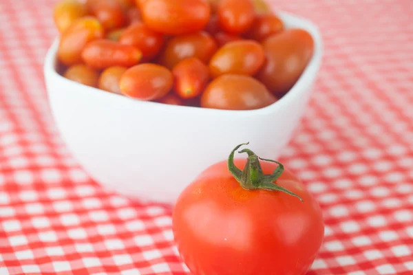 Pomodoro ciliegia e pomodoro in ciotola su tessuto a quadretti — Foto Stock