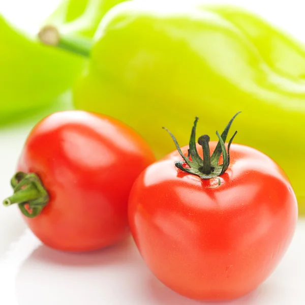 Tomaten en groene paprika's geïsoleerd op wit — Stockfoto