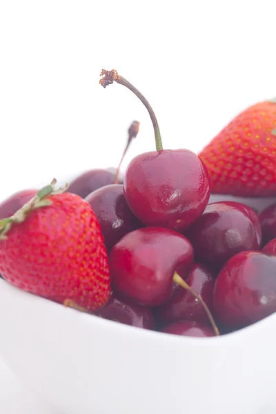 Cerezas y fresas en un tazón de cerámica aislado en blanco —  Fotos de Stock