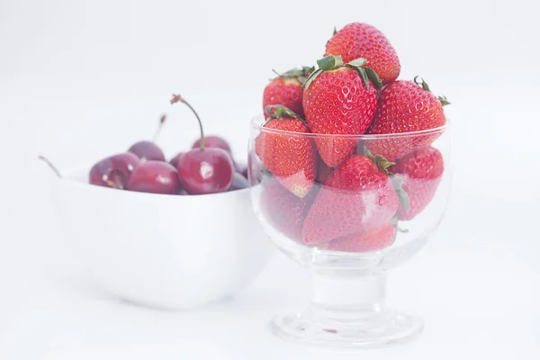 Cerezas y fresas en un tazón de cerámica y vidrio aislado en —  Fotos de Stock