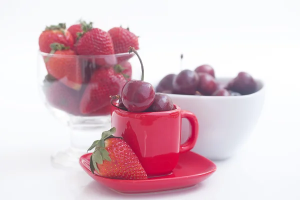 Cerezas y fresas en un tazón de cerámica y vidrio aislado en —  Fotos de Stock