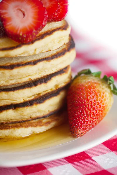 Pannkakor, honung och jordgubbar på rutig tyg — Stockfoto