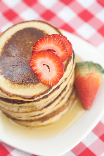 Pannkakor, honung och jordgubbar på rutig tyg — Stockfoto