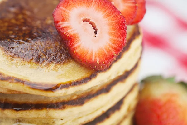 Pannkakor, honung och jordgubbar på rutig tyg — Stockfoto