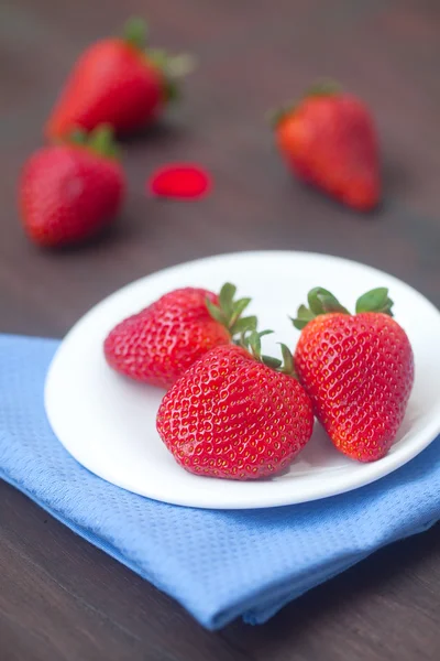 Fragola succosa rossa in un piatto su una superficie di legno — Foto Stock