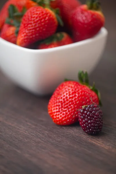 Fragola succosa rossa in una ciotola e mora su una surfa di legno — Foto Stock