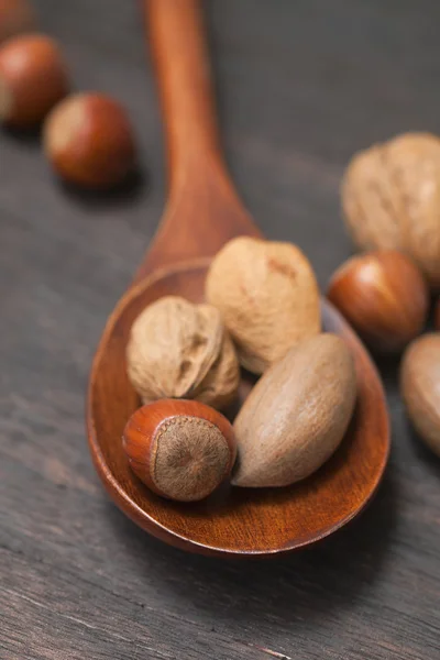 Wooden spoon with nuts on a wooden surface — Stock Photo, Image
