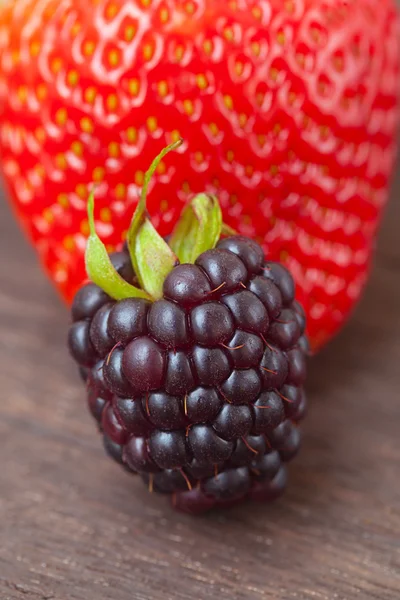 Rote saftige Erdbeere und Brombeere auf einer Holzoberfläche lizenzfreie Stockfotos