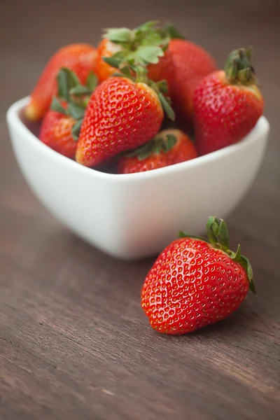 Röd saftiga jordgubbar i en skål på en trä yta — Stockfoto