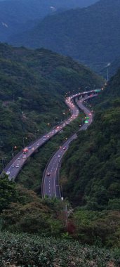 The curved highway through the green rice fields with houses scattered throughout the plain in Yilan, Taiwan - Aerial view of National Freeway No.5, Taipei-Ilan Section in Ilan, Taiwan, Asia