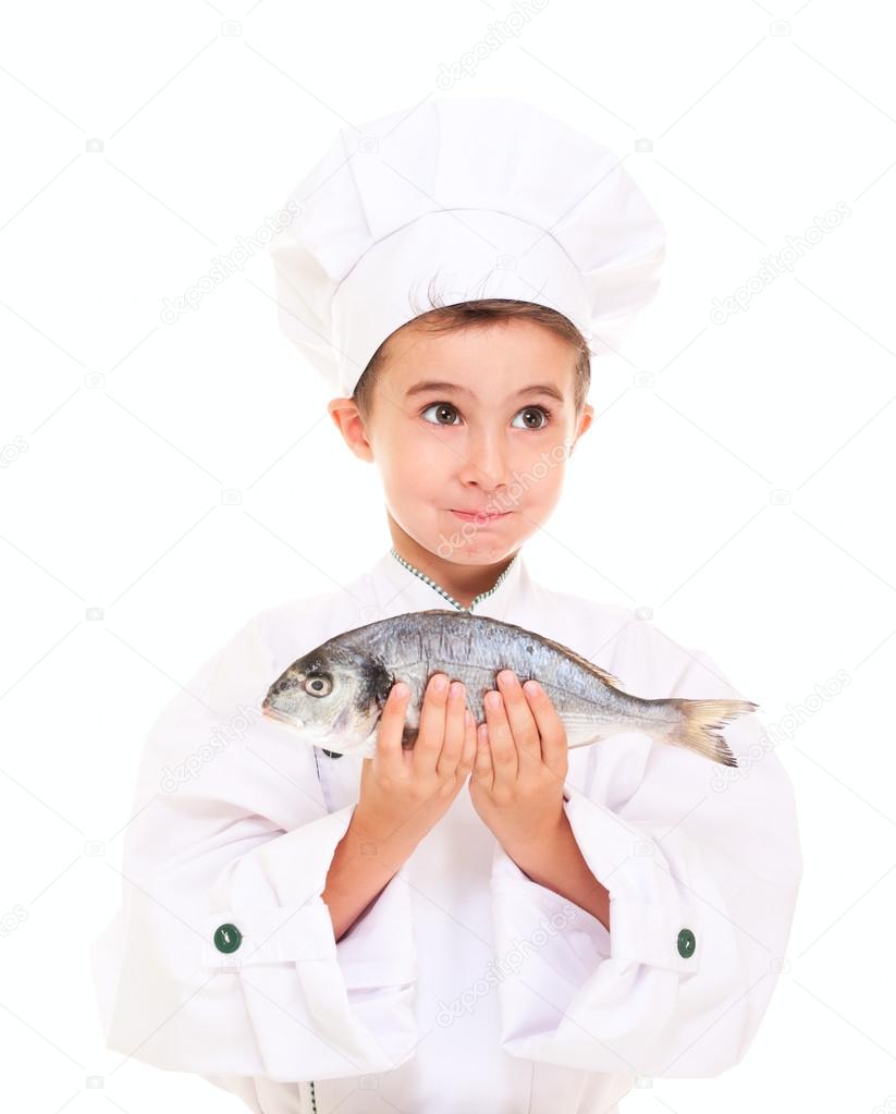 Little boy chef in uniform surprised holding dorado fish