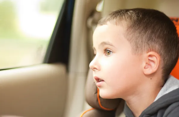 Nieuwsgierig kleine jongen in de auto die kijken naar het venster Rechtenvrije Stockfoto's