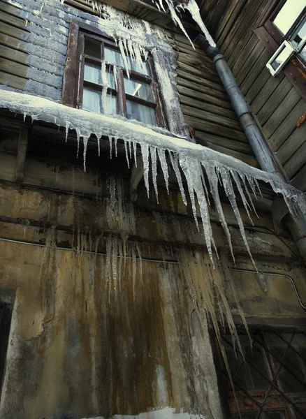 Großer Eiszapfen und altes Haus — Stockfoto