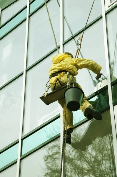 Чистильщик окон забирается на фасад небоскреба — стоковое фото