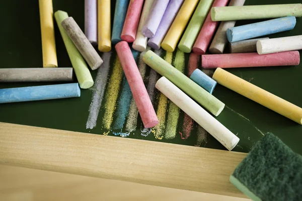Veelkleurige krijtjes en krijt gum op het bord — Stockfoto