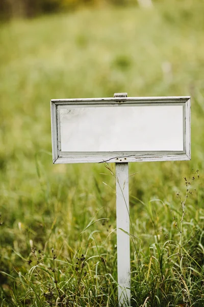 Empty signboard on a green field — Stock Photo, Image