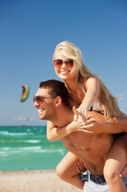 Happy couple in sunglasses on the beach clipart