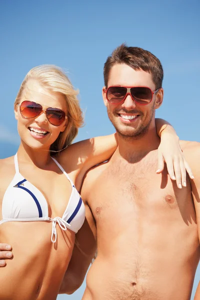 Casal feliz em óculos de sol na praia — Fotografia de Stock