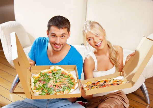 Romantiska par äta pizza hemma Royaltyfria Stockfoton