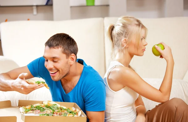 Pareja comiendo diferentes alimentos — Foto de Stock