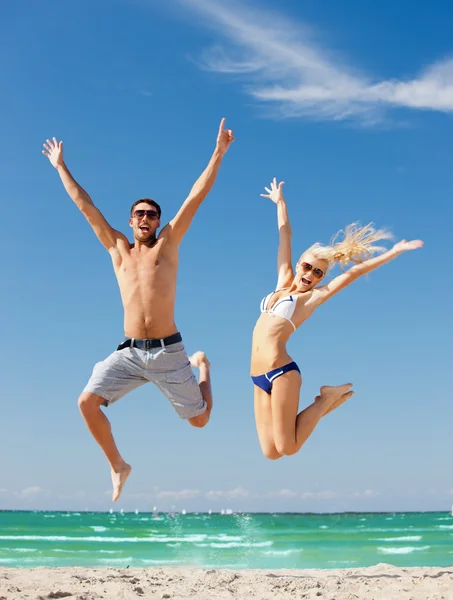 Pareja feliz saltando en la playa — Foto de Stock