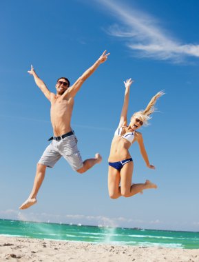 Happy couple jumping on the beach clipart