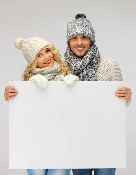 Casal em uma roupa de inverno segurando placa em branco — Fotografia de Stock