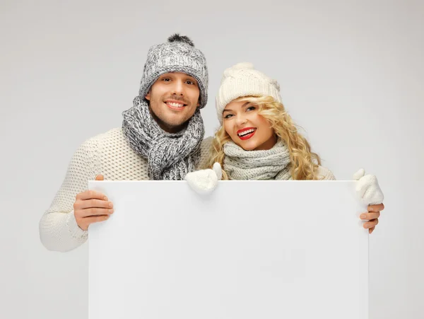 Pareja en una ropa de invierno sosteniendo tablero en blanco — Foto de Stock