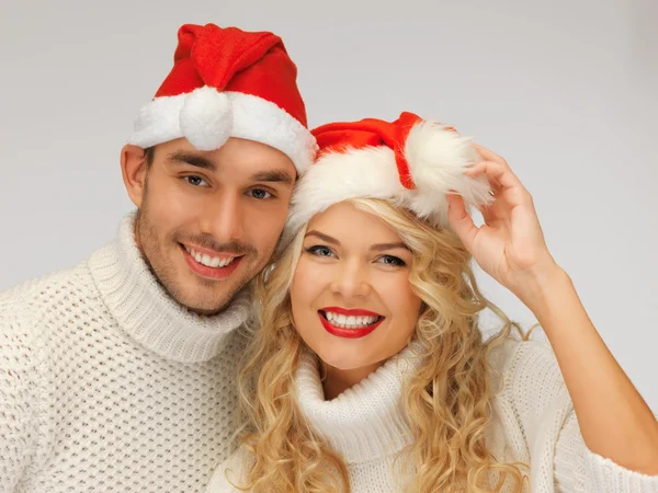 Familienpaar in Pullovern und Weihnachtsmannhüten — Stockfoto