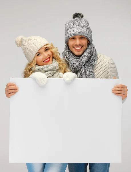 Couple in a winter clothes holding blank board — Stock Photo, Image