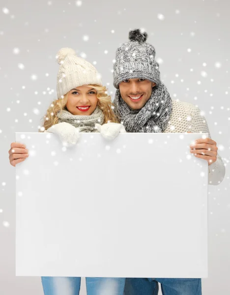 Pár v zimní oblečení drží prázdná deska — Stock fotografie